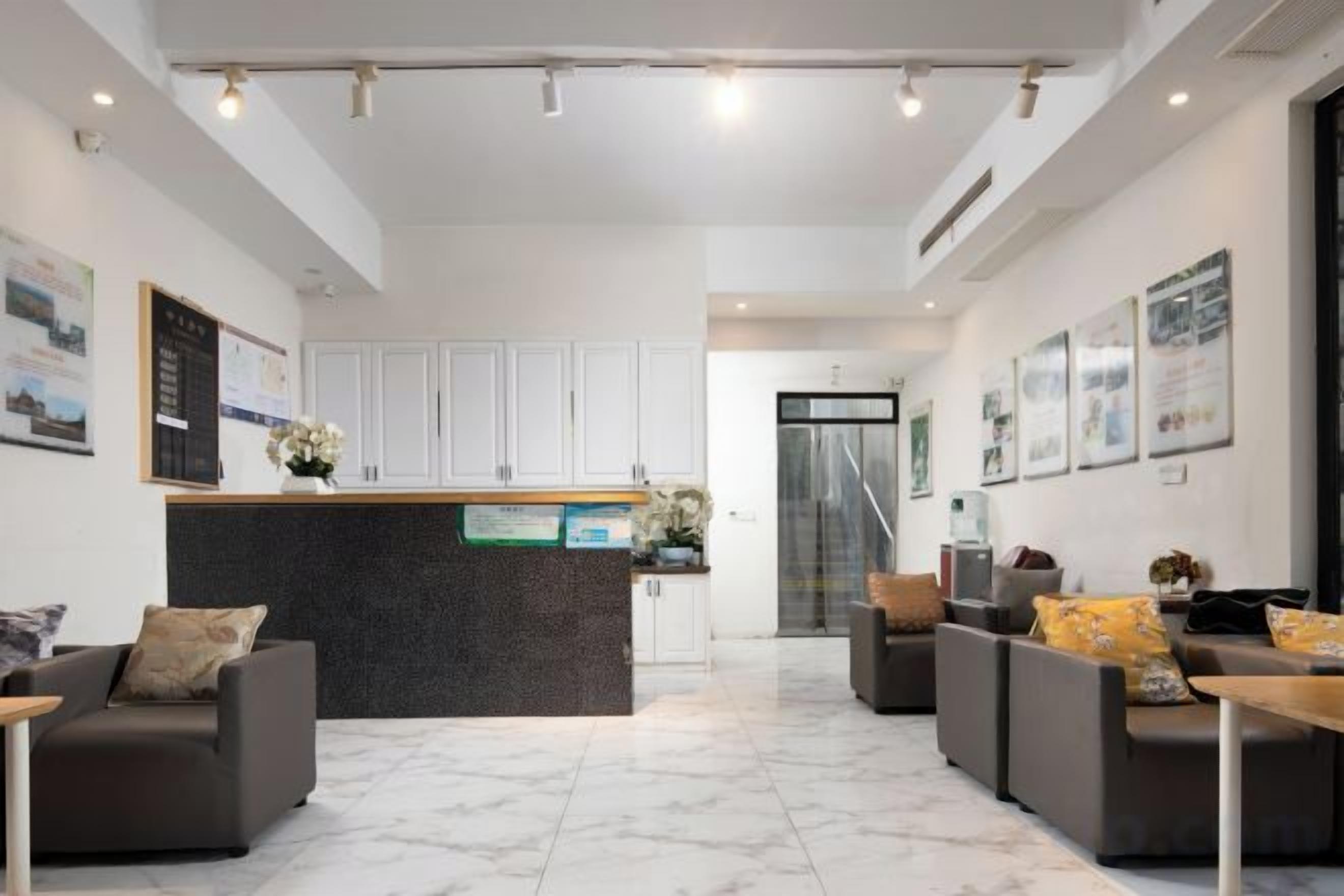 Un hall d’hôtel comprenant un comptoir d’accueil, un espace salon et un escalier menant aux étages supérieurs.