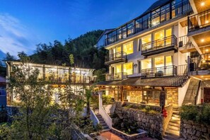 Un edificio de varios pisos con balcones, fachada de piedra y una entrada bien iluminada.