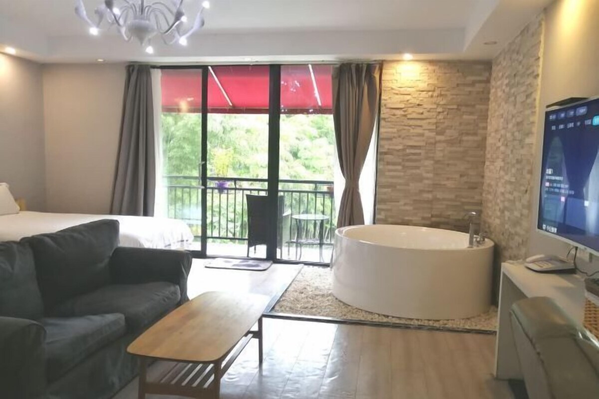 Une chambre d’hôtel avec un lit, un canapé, une petite table, une baignoire et un téléviseur.