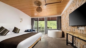 Un dormitorio con una cama grande, una pared de piedra, un televisor de pantalla plana, una bañera y un balcón con vistas.