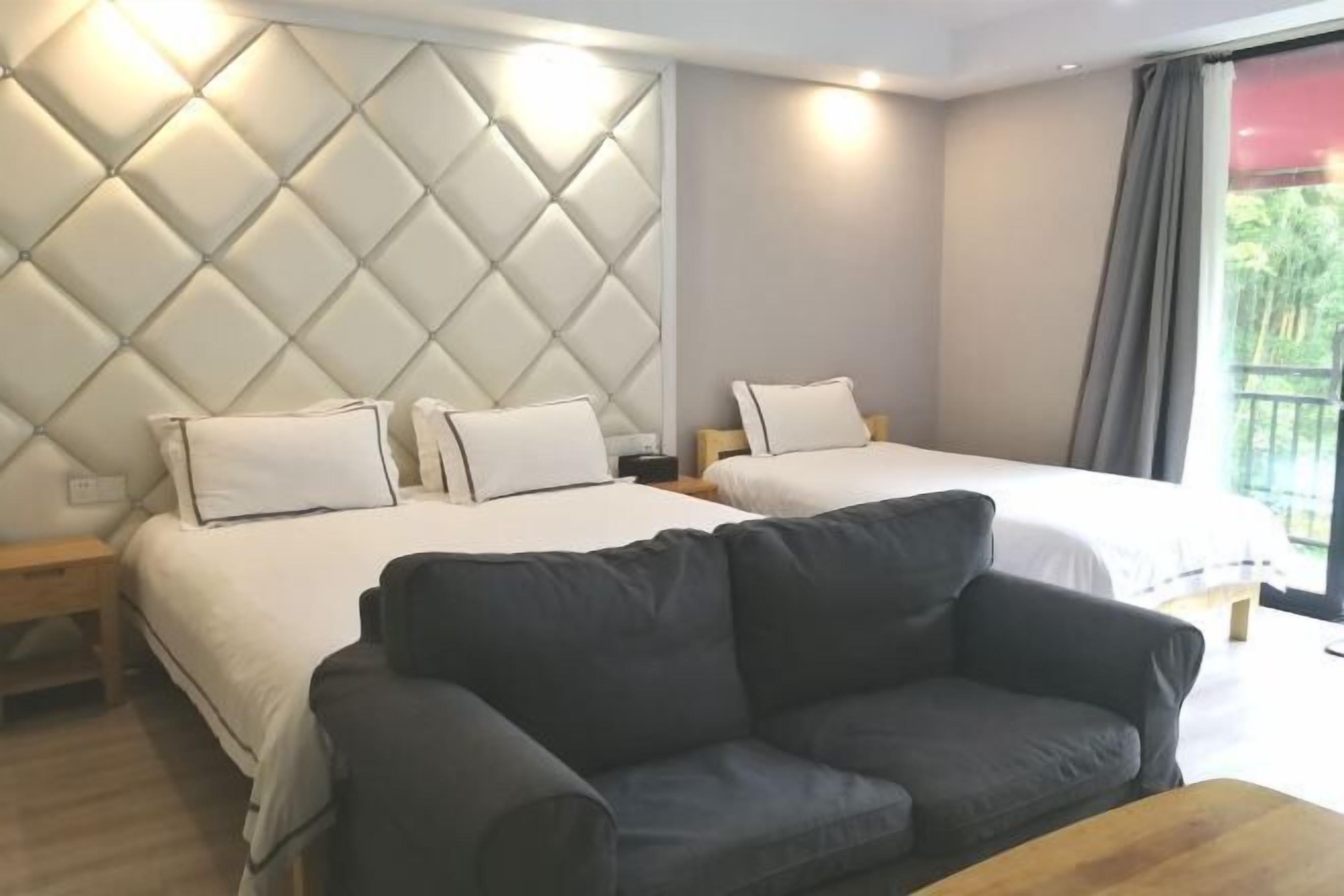 Une chambre d’hôtel avec deux lits, un canapé et une grande fenêtre avec des rideaux.