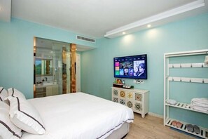 Een slaapkamer met een bed, een televisie, een kledingkast en een schoenenrek.