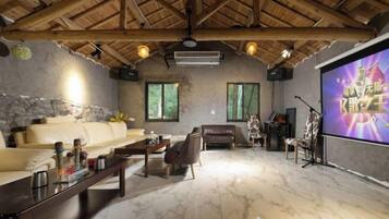 A living room with a high ceiling, a sofa, a coffee table, and a television screen.
