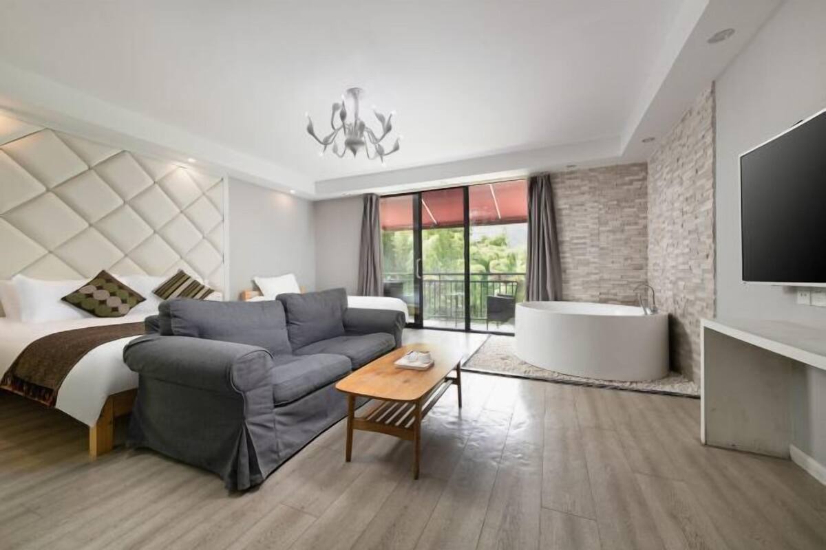 Een moderne hotelkamer met een bed, een bank, een salontafel, een televisie en een bad.