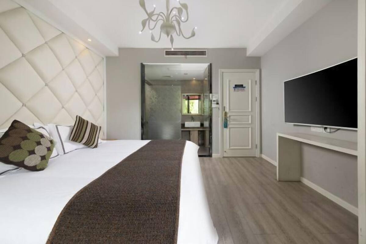 Een hotelkamer met een bed, een televisie en een badkamer zichtbaar door een geopende deur.