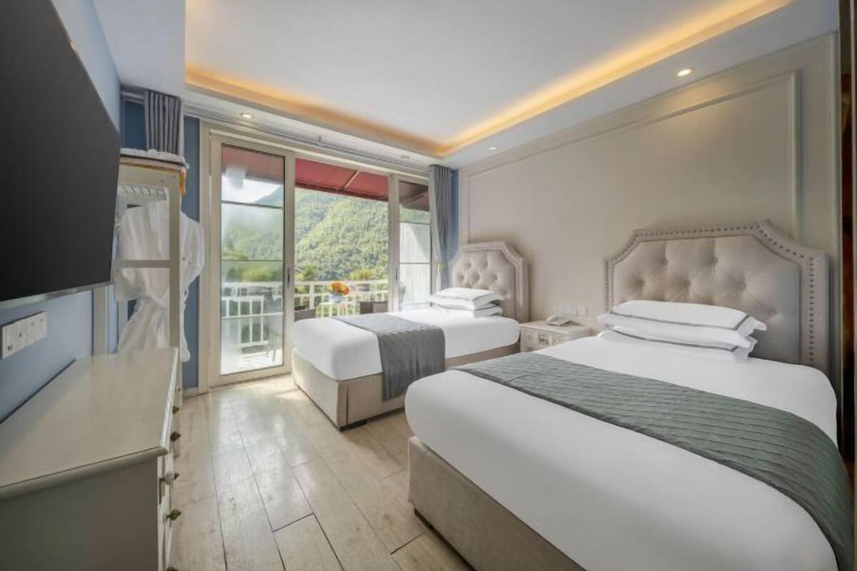 Een hotelkamer met een groot bed, een nachtkastje, een kledingkast en uitzicht op een balkon met een hekwerk.
