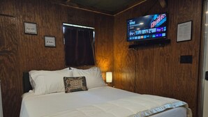 Habitación de hotel con una cama grande, un televisor montado en la pared y paneles de madera.