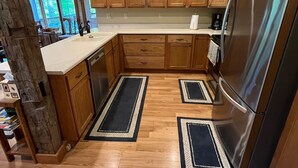 A kitchen with wooden cabinets, a stainless steel refrigerator, and a large window.