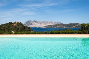 Una piscina azul cristalina con vistas a un paisaje montañoso y una masa de agua.