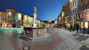 Una plaza con una fuente central, rodeada de edificios históricos con tiendas y cafés.