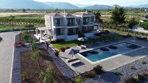 A modern multi-story building with a swimming pool, outdoor seating, and a view of the surrounding landscape. - Almyres Luxurious Residences  (Argos-Mykines)