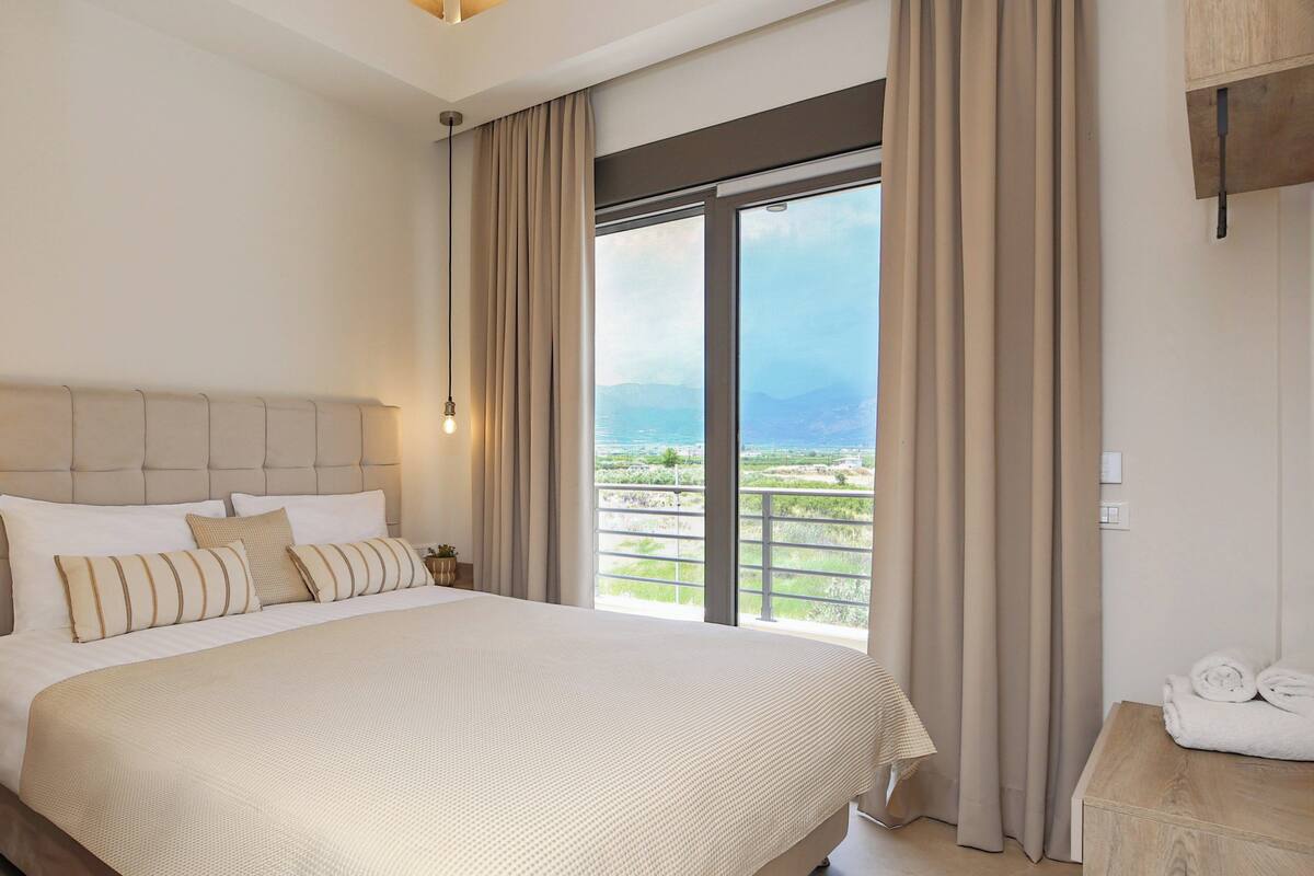 Un dormitorio amplio con una cama grande, vistas al exterior y techo de madera.