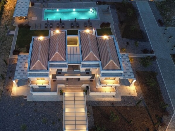 A modern two-story building with a swimming pool, multiple balconies, and a covered patio area.