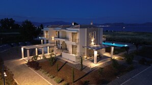 A modern two-story house with a swimming pool, outdoor seating, and a view of the sea. - Almyres Luxurious Residences  (Argos-Mykines)