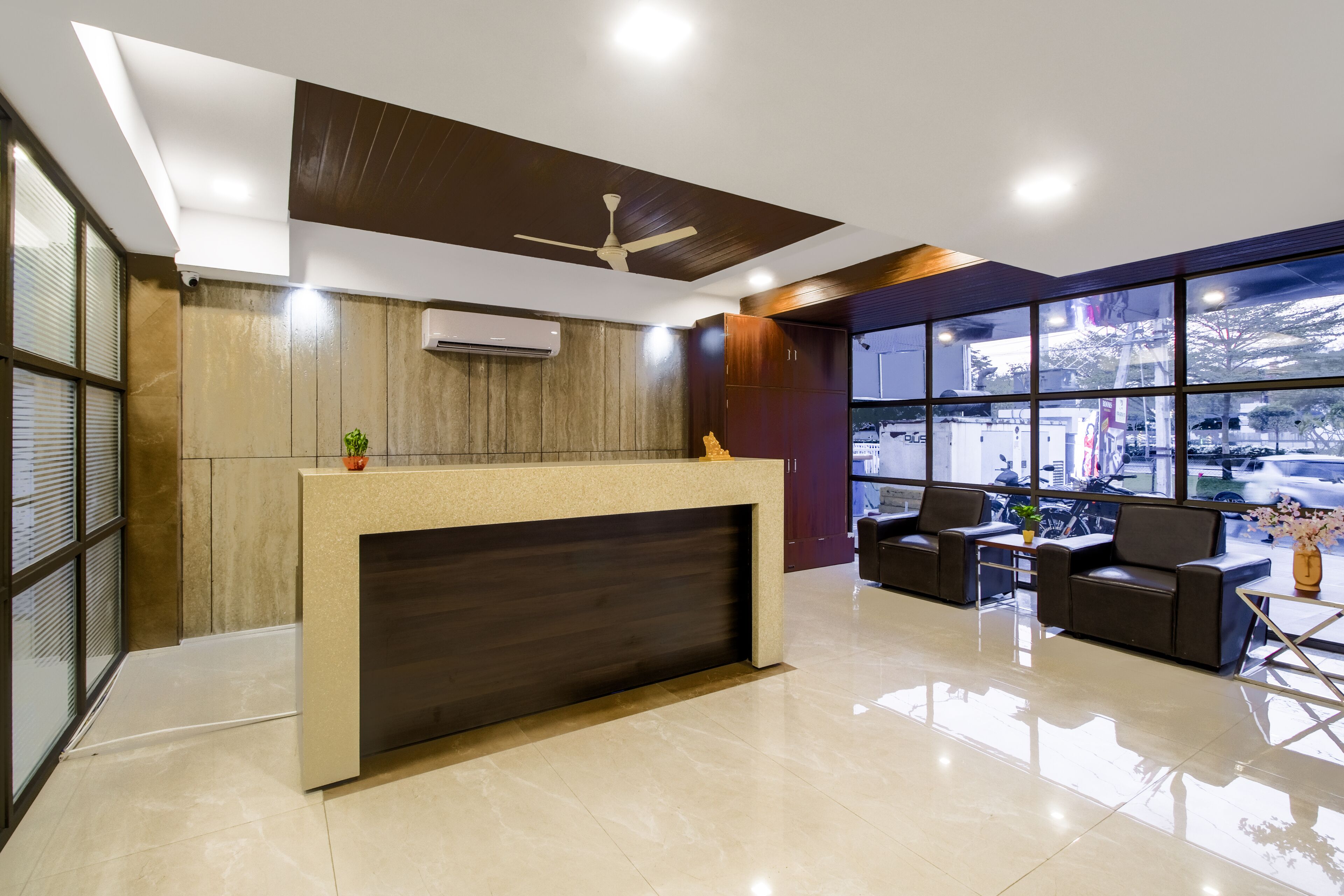 A modern reception area with a counter, seating, and large windows.