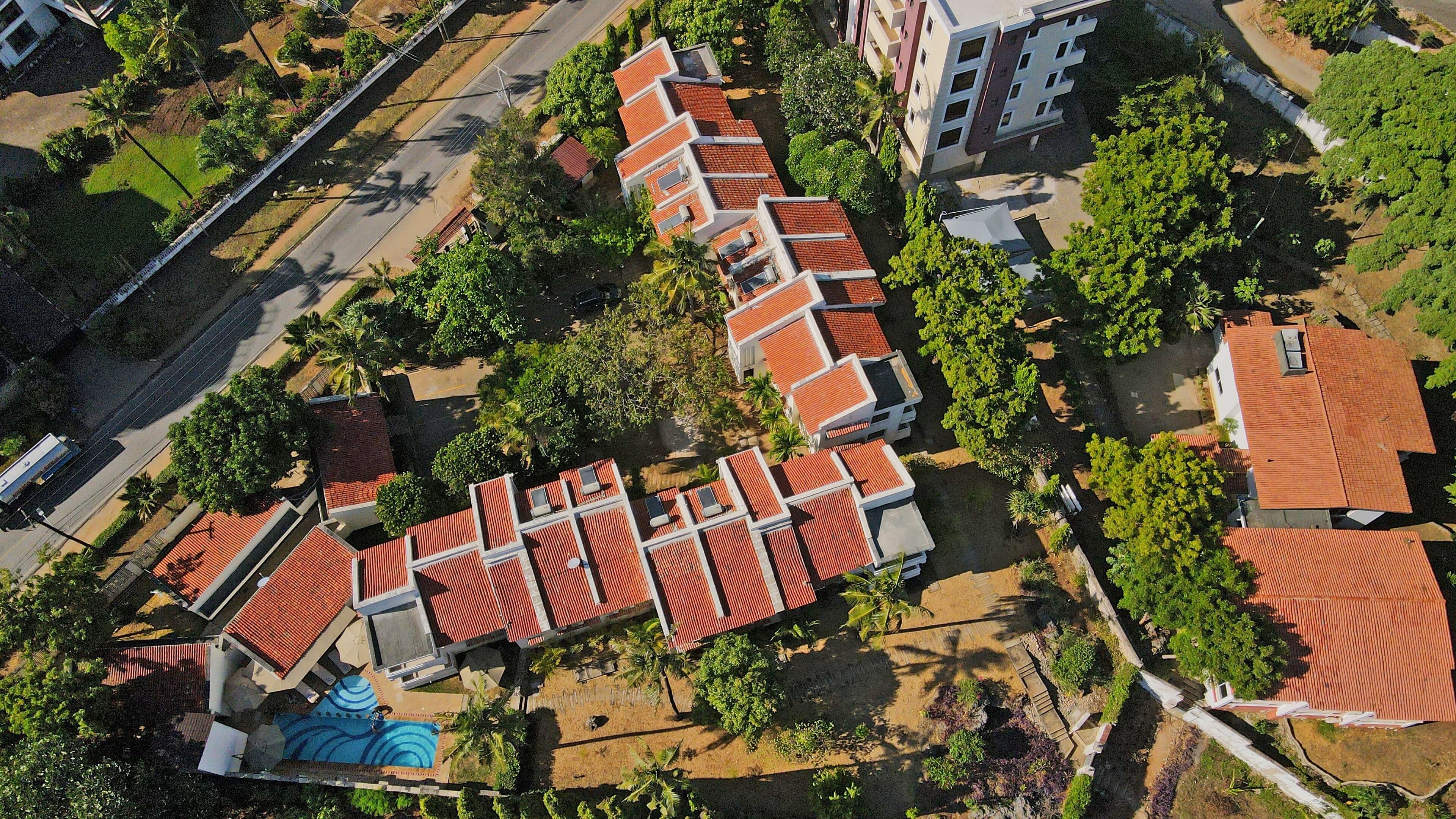 An aerial view of a residential area with terraced houses, a swimming pool, and a mosque.