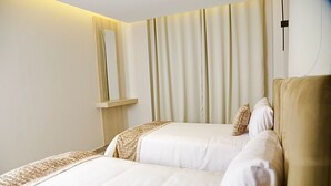 Habitación de hotel con dos camas, un espejo grande y una cortina.