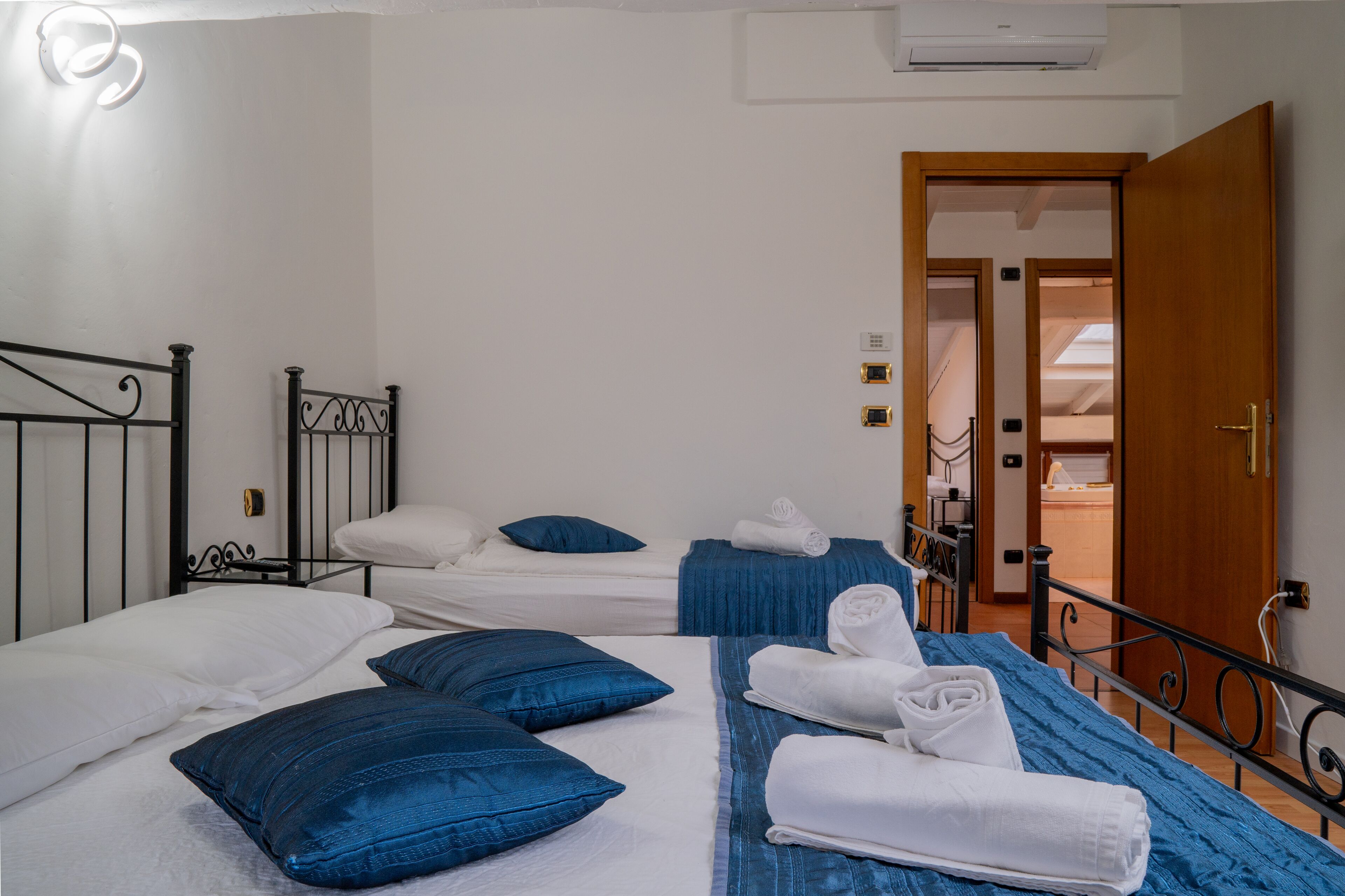 A hotel room with two beds, each with blue bedding and white pillows. There are towels neatly folded on the beds.