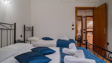 A hotel room with two beds, each with blue bedding and white pillows. There are towels neatly folded on the beds.