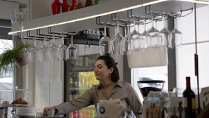 Een bar met een toonbank, wijnglazen en een koffiekop.