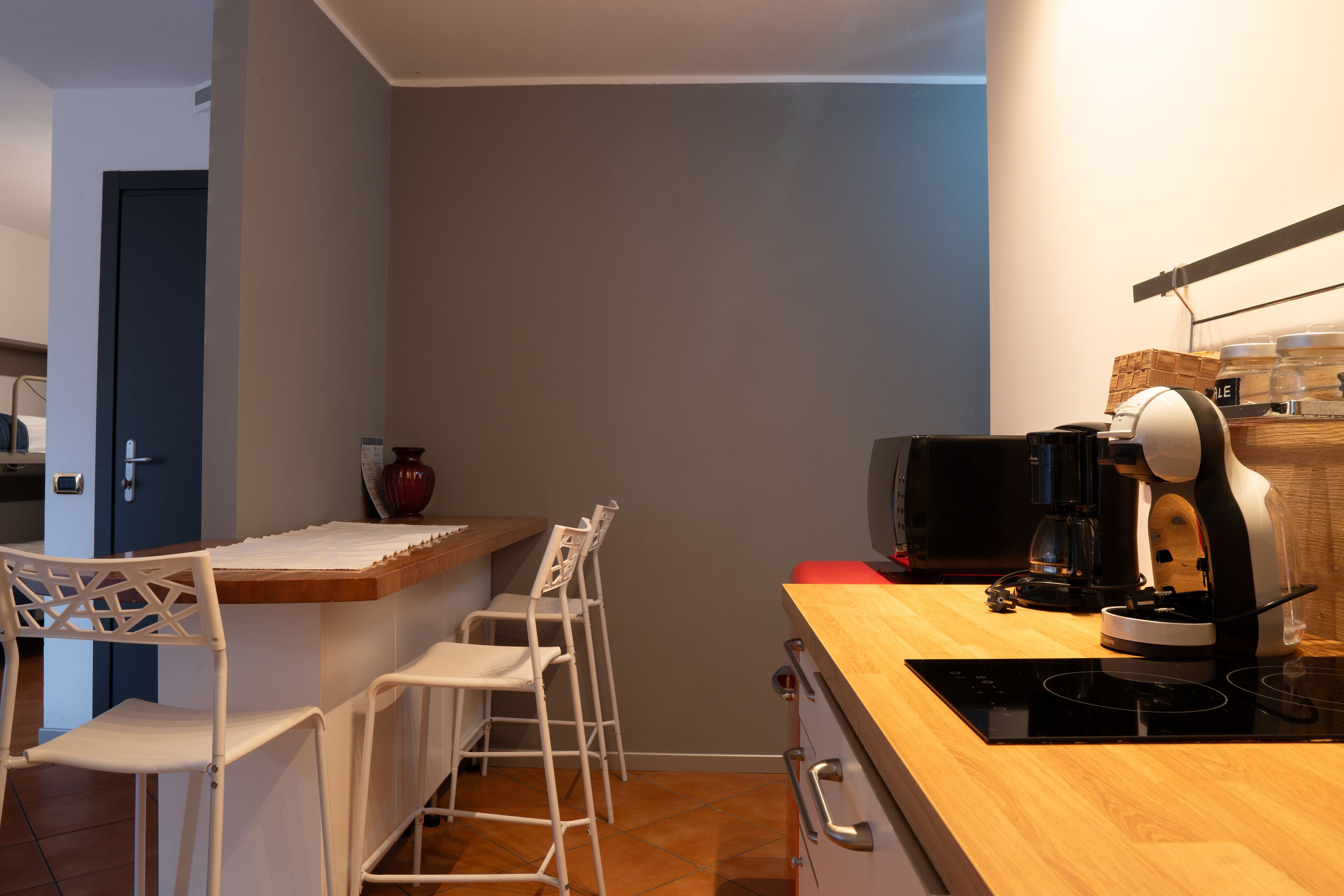A compact kitchen with a wooden countertop, a coffee maker, and a small refrigerator.