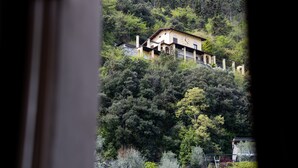 Een huis op een heuvel met een balkon en uitzicht op het omliggende bos.