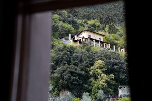 Una casa en una colina con un balcón y vistas al bosque circundante.