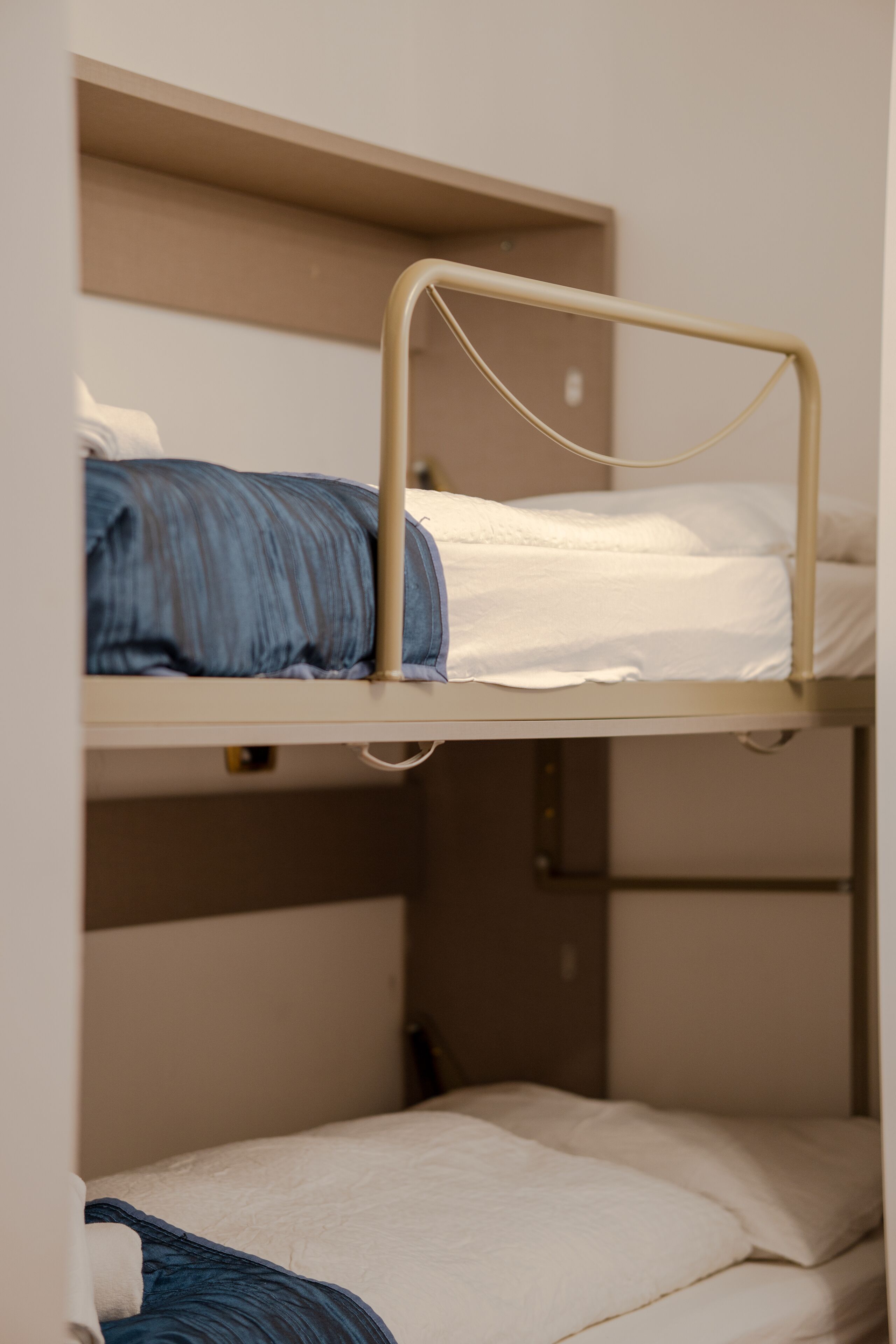 Uma cama de solteiro com estrutura metálica e roupa de cama branca.