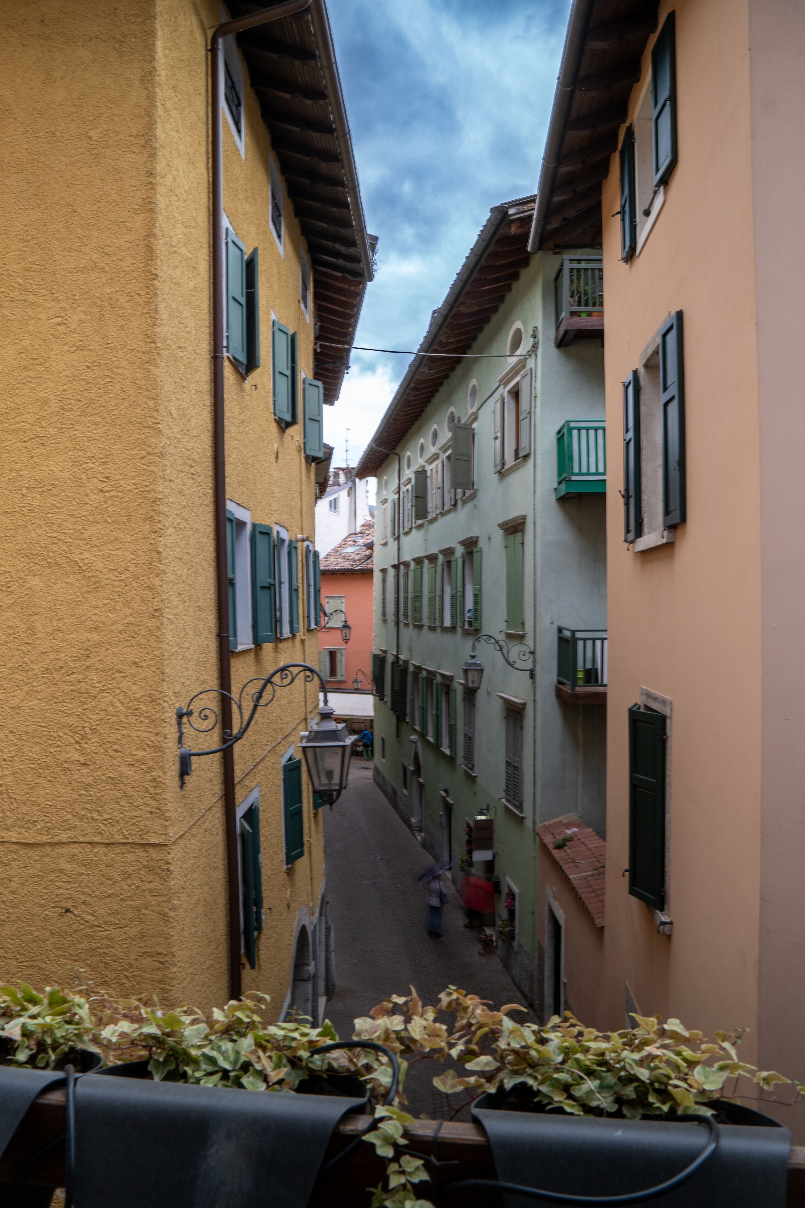 Una calle estrecha flanqueada por edificios con balcones y contraventanas.