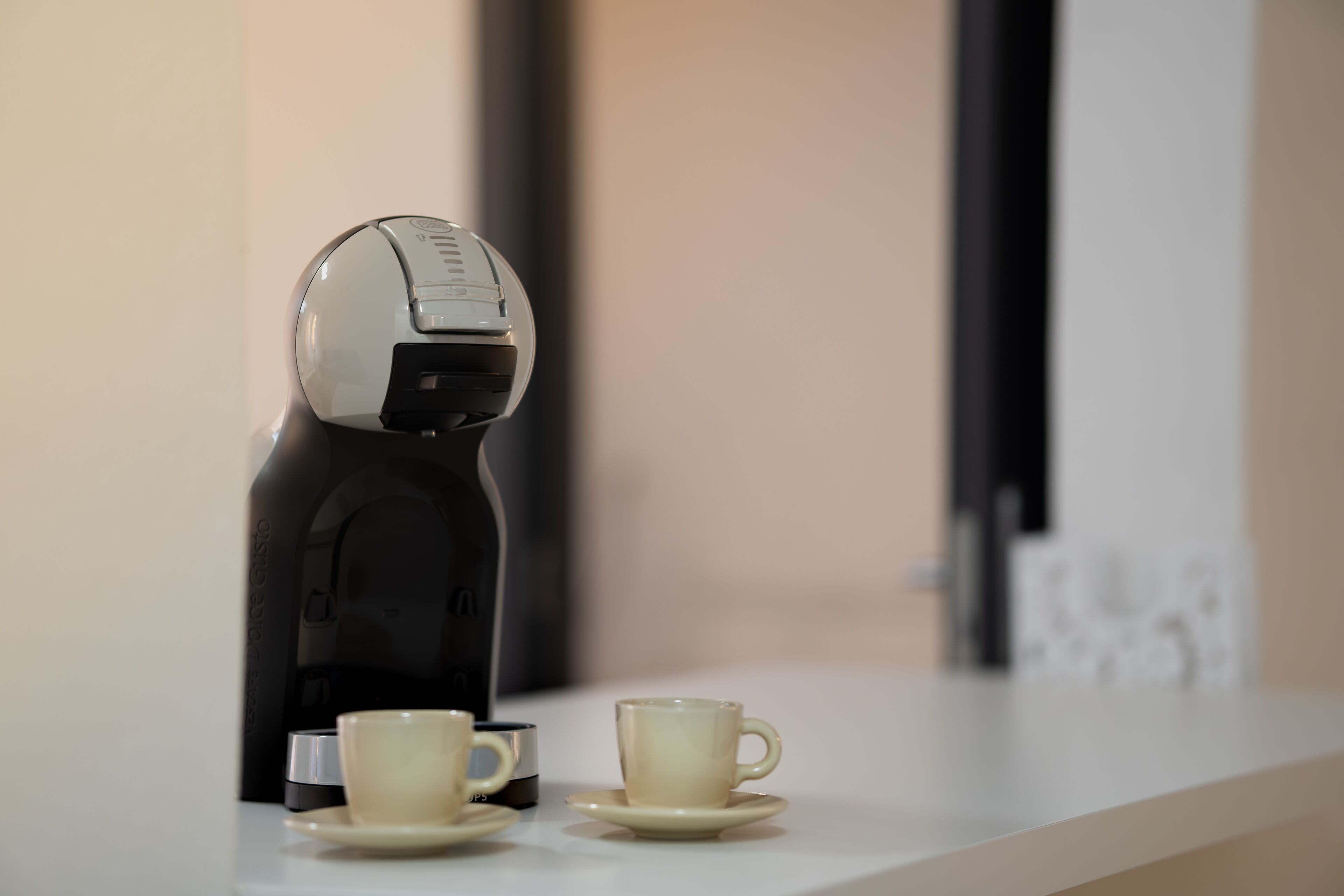 Uma máquina de café e duas chávenas sobre um balcão.