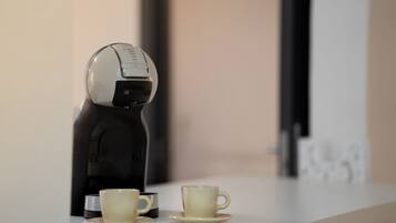 Uma máquina de café e duas chávenas sobre um balcão.