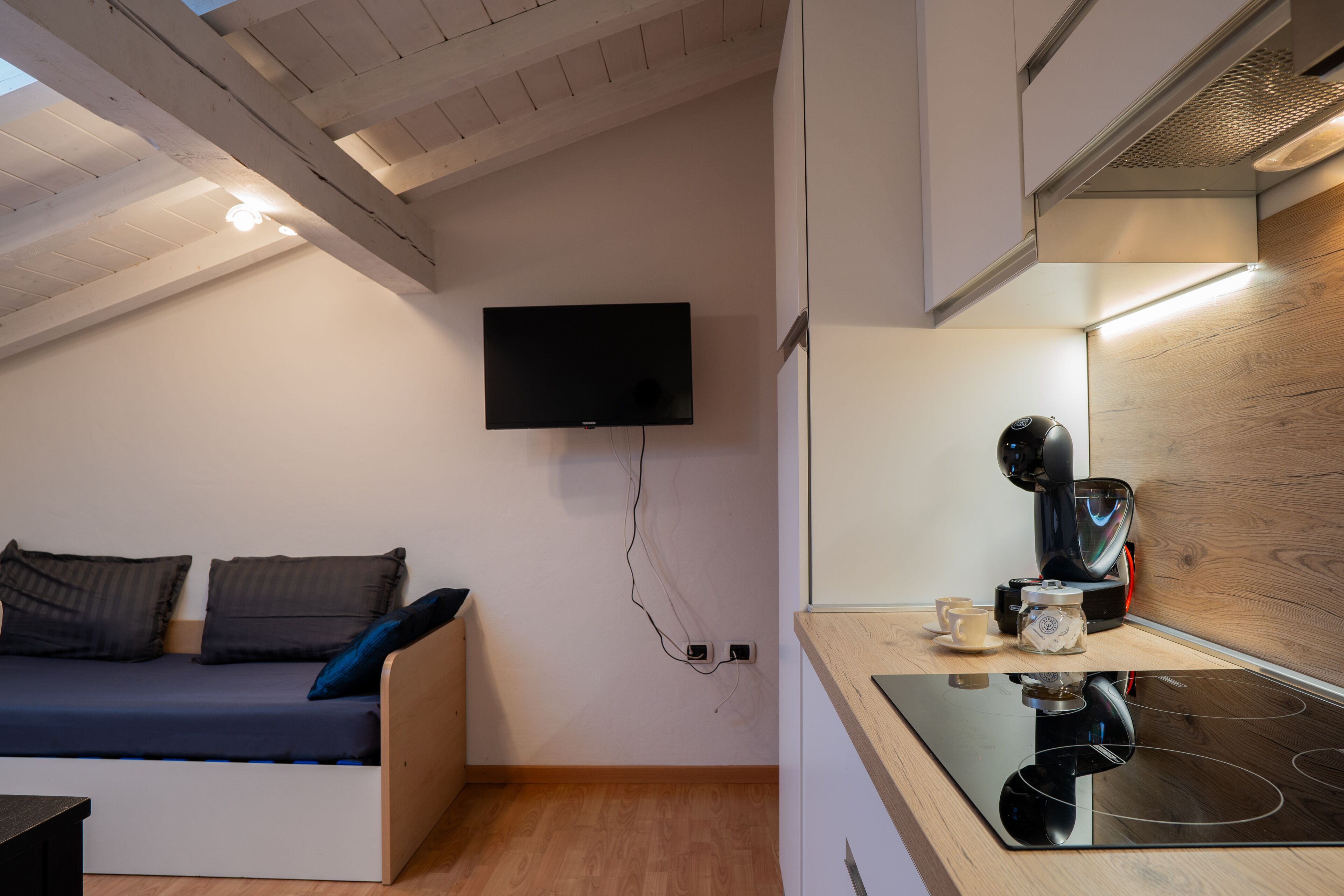 Een moderne keuken met een ingebouwde kookplaat, een flatscreen-tv aan de muur en een houten plafond.