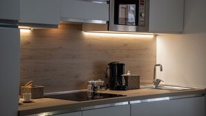 Een moderne keuken met een ingebouwde magnetron, een koffiezetapparaat en een spoelbak.