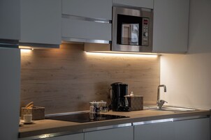 Una cocina moderna con microondas integrado, cafetera y fregadero.