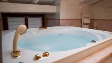 A bathtub with a showerhead, a control knob, and a brand name label.