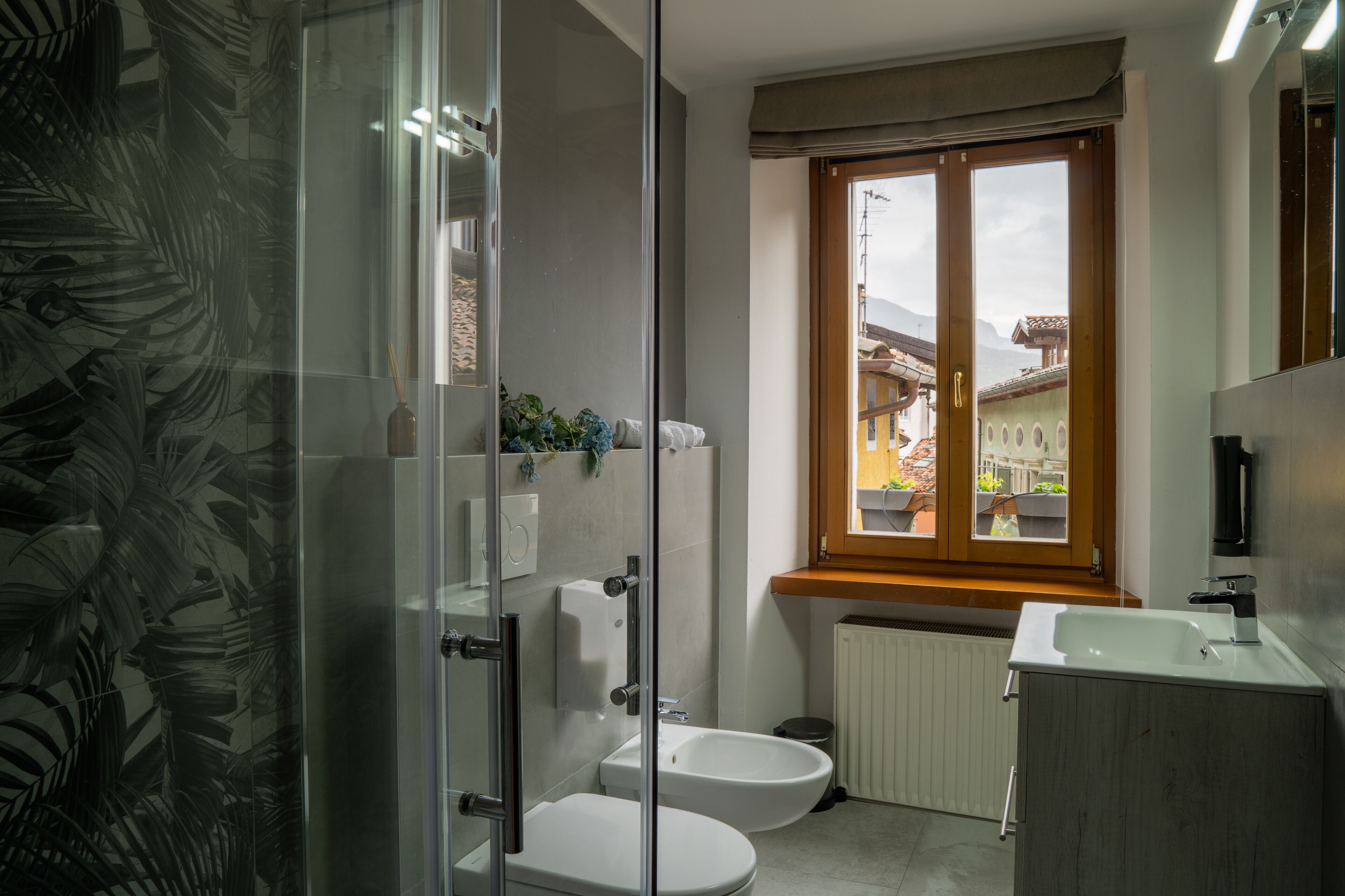 Een moderne badkamer met een douchecabine van glas, een toilet, een bidet en een wastafel.
