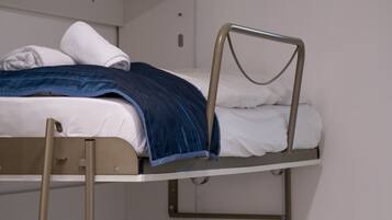 Una cama litera con ropa de cama blanca y una manta azul.