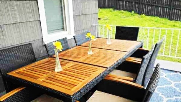 Eine Terrasse im Freien mit einem Holztisch und Korbstühlen.