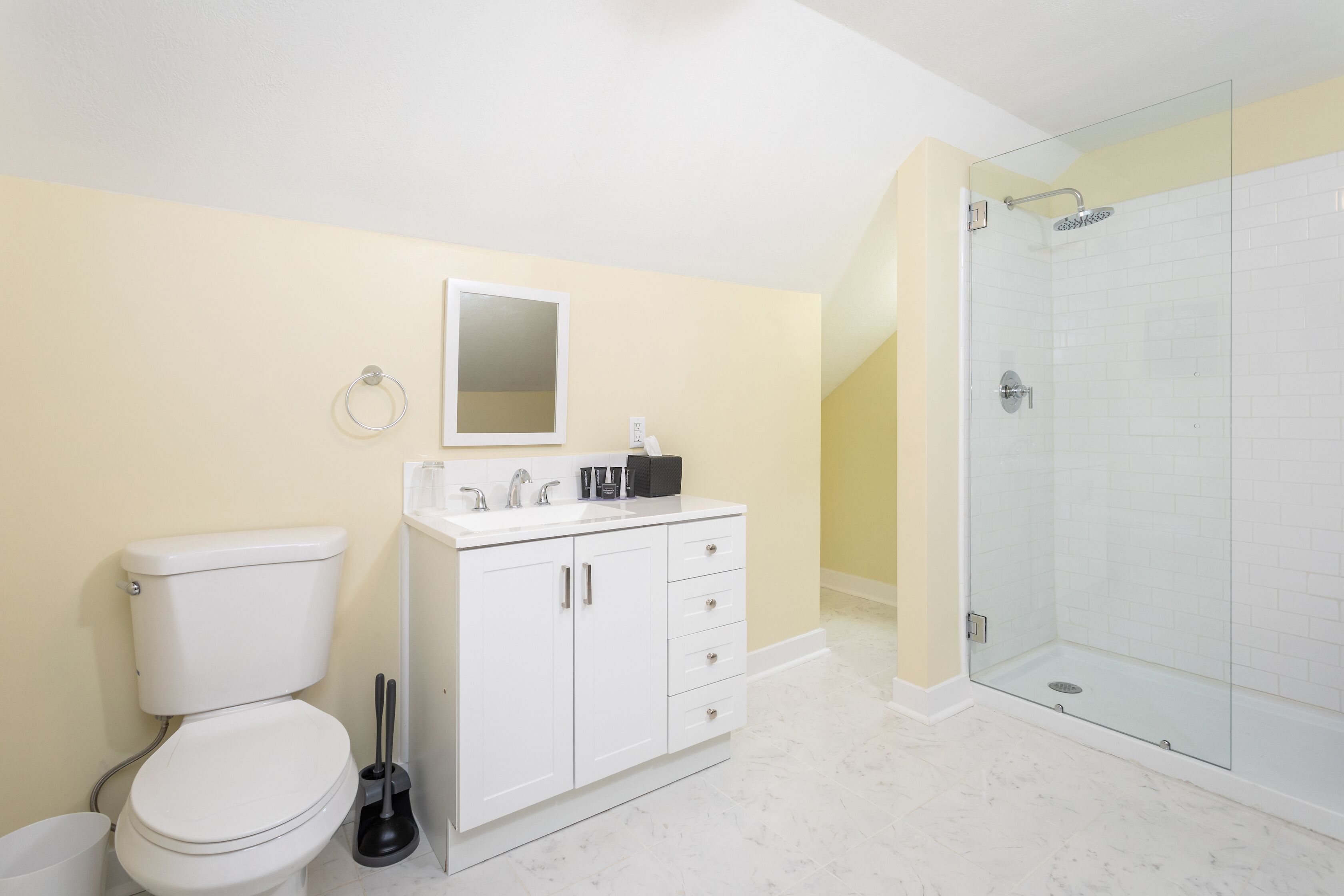 A bathroom with a toilet, sink, mirror, and shower.
