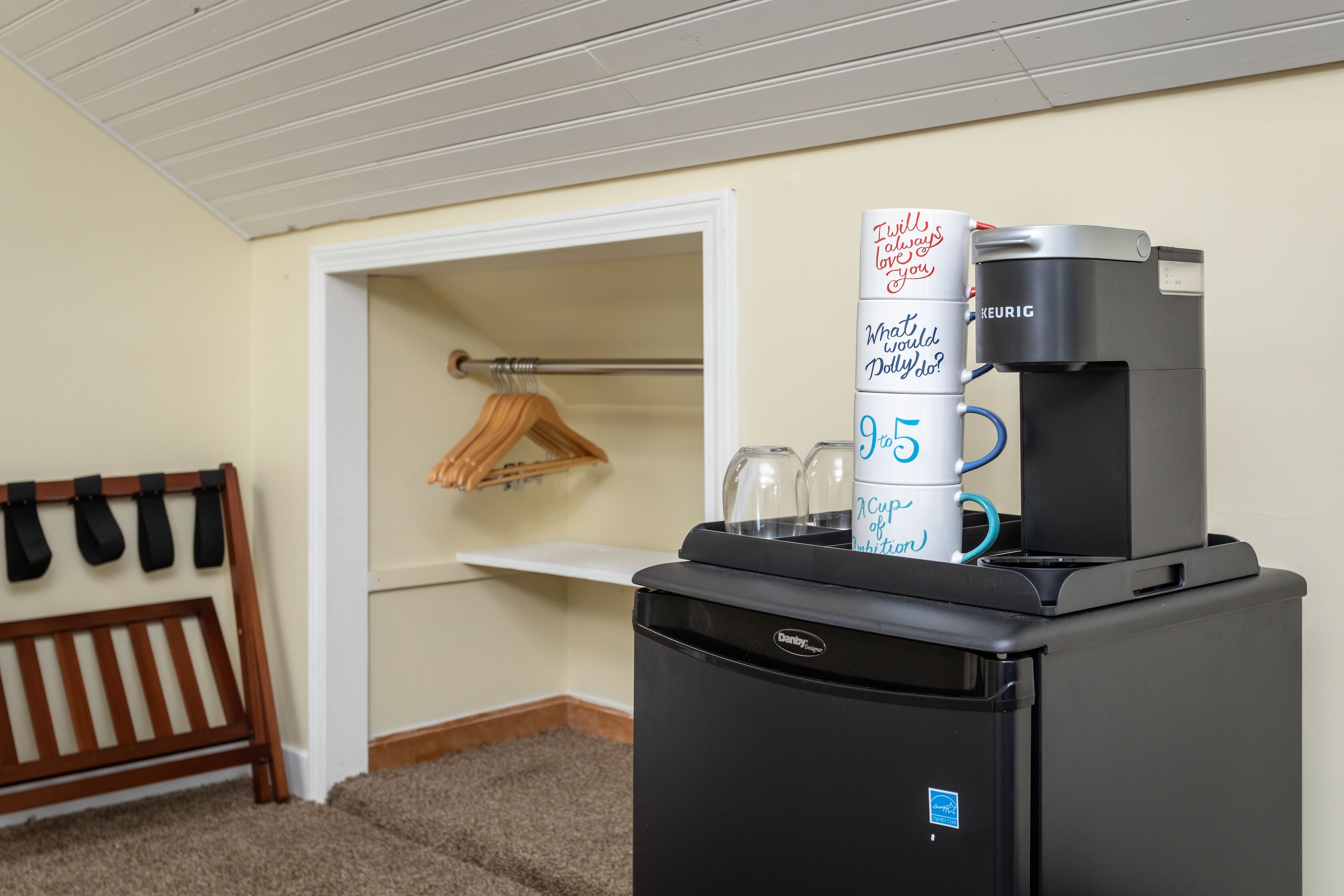 Una habitación con cafetera, un refrigerador Danby y un banco de madera.