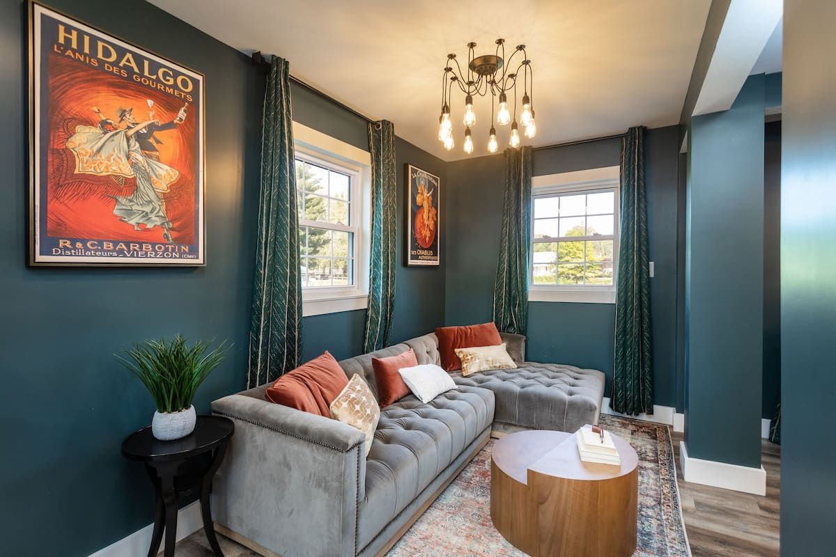 A modern living room with a grey sectional sofa, a round wooden coffee table, and a chandelier.