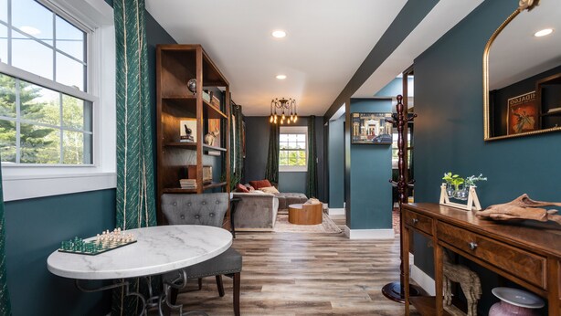 A room with a marble table, a bookshelf, a sofa, and a wooden console table. - The Legacy Inn (Luray)