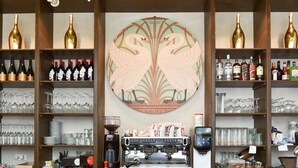 Un espace bar avec des étagères remplies de bouteilles de vin, de verres et un appareil à café.