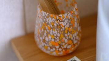 Uno spazzolino in una tazza decorata su un ripiano di legno, vicino a una confezione di sapone al limone.