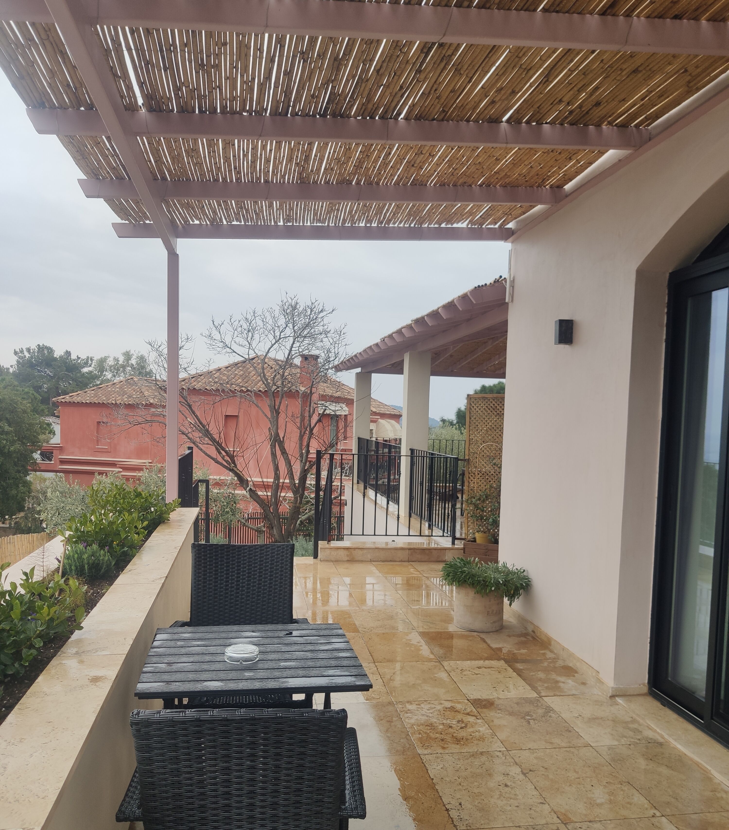 A covered patio area with a pergola, a tiled floor, and outdoor furniture.