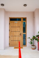 Una puerta de madera con un letrero que dice "EIZOAOZ ENTRANCE" y una planta en maceta a la derecha.