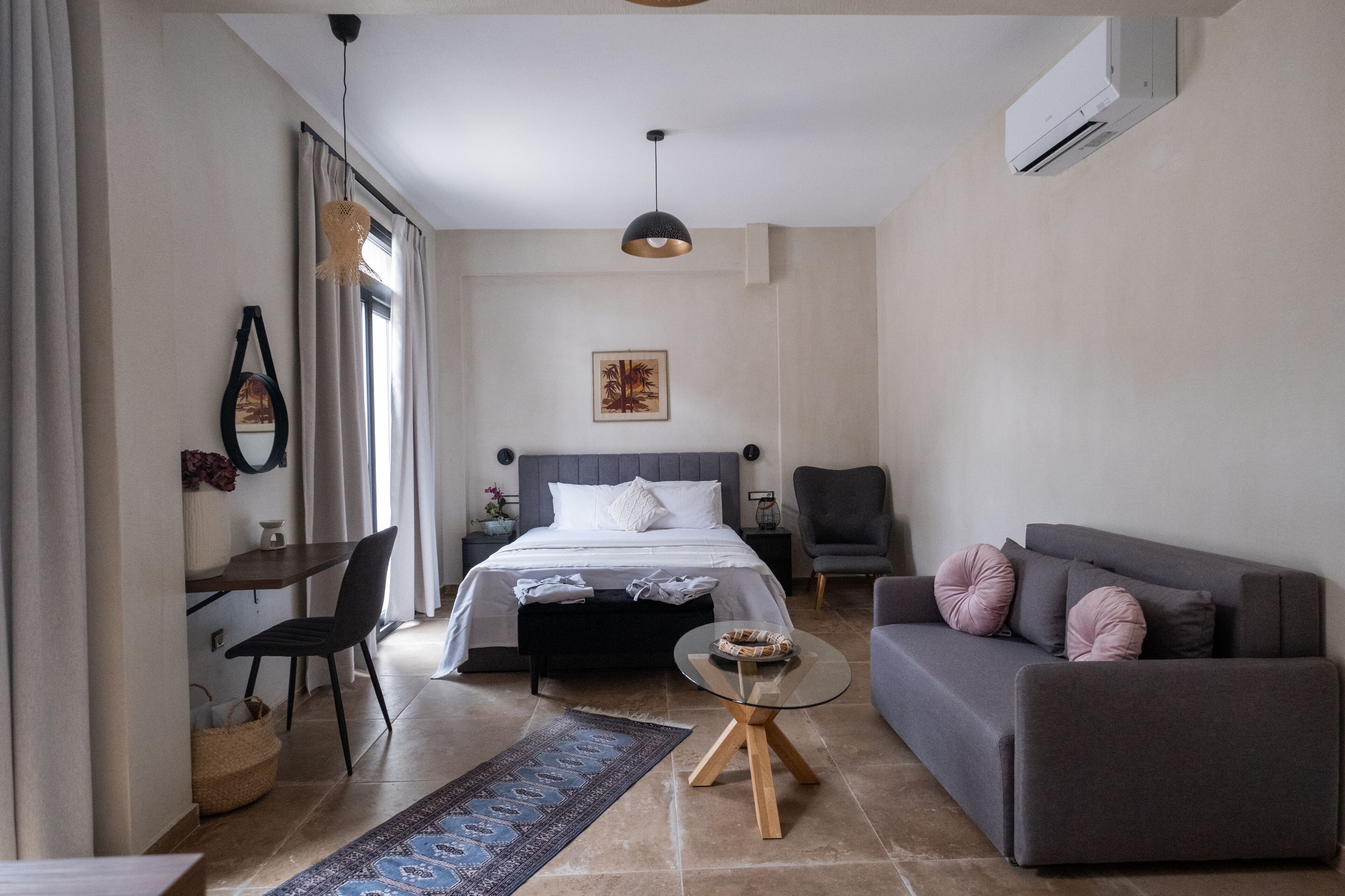 A modern bedroom with a bed, bedside table, chair, and a sofa.