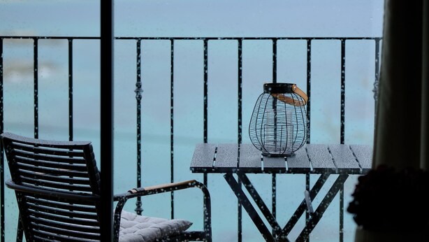 A balcony with a metal railing, a table, and a chair. - blue crystal view (Pangaio)