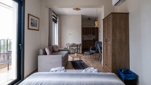 A modern hotel room with a bed, a sofa, a dining table, and a kitchen area. - blue crystal view (Pangaio)