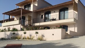 A two-story house with a balcony, a covered patio, and a sandy driveway. - blue crystal view (Pangaio)